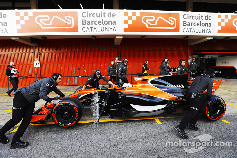 Los miembros del equipo McLaren empujan el McLaren MCL32 de Fernando Alonso, McLaren, al pit lane