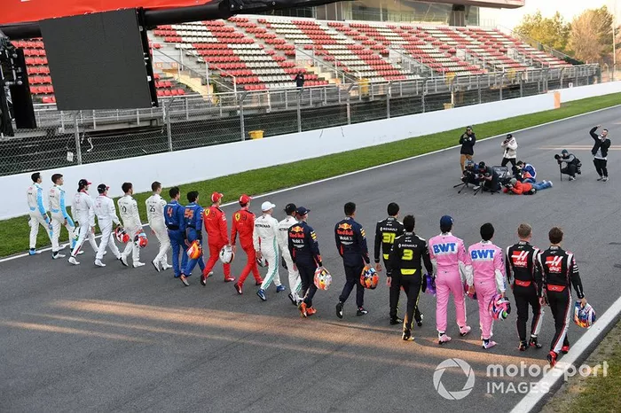 The drivers walk along the track toward a group of photographers