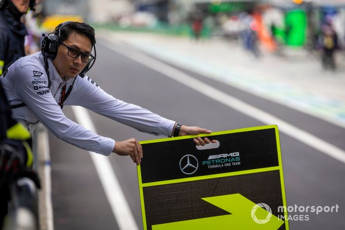 Un miembro del equipo Mercedes AMG sostiene un cartel en el pit lane 