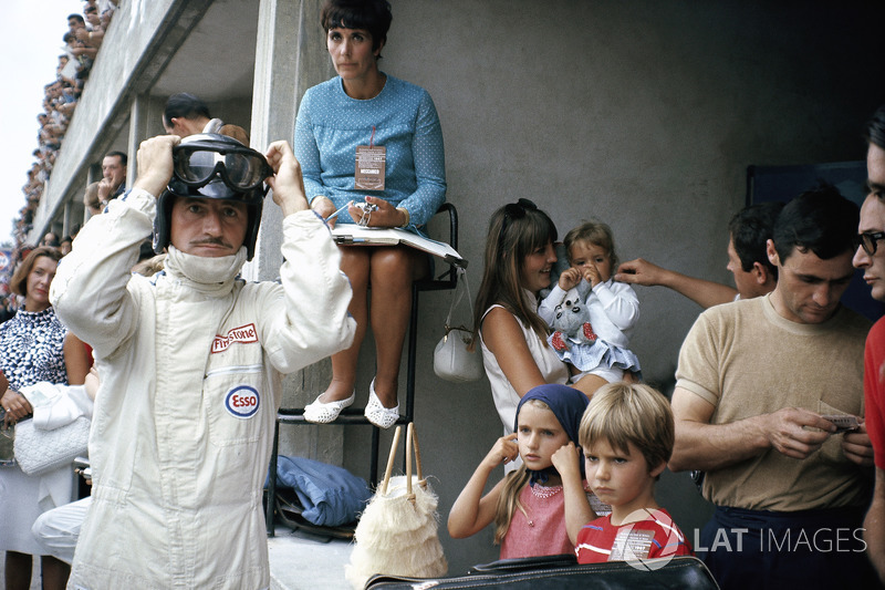 Graham Hill se prepara para competir en boxes, rodeado de su familia: su esposa Bette Hill y una niñera que cuida a los tres niños - más adelante F1 mundo campeón Damon