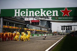 Performers in Chinese dragon costumes on the grid beneath a Heineken bridge and start light gantry