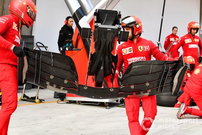 Mecânicos da Ferrari com asa dianteira do SF90
