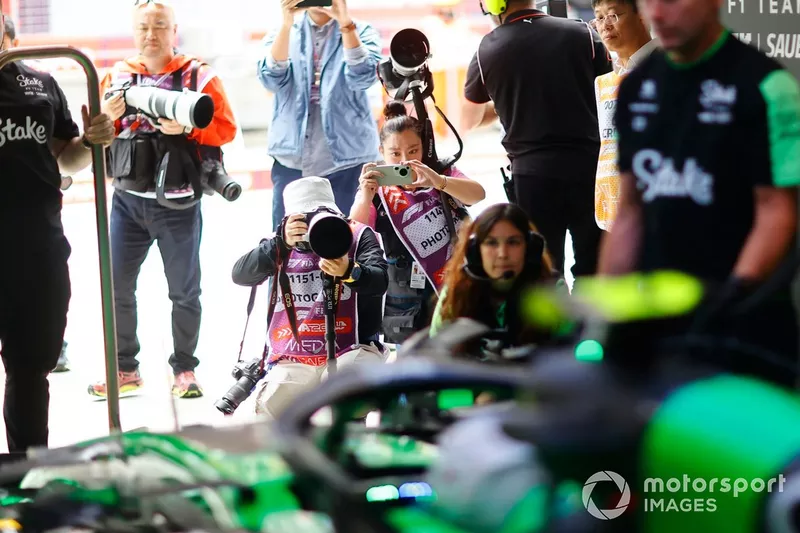 Des photographes se tiennent devant le garage pour prendre des photos de la voiture de Zhou Guanyu, Kick Sauber C44. 
