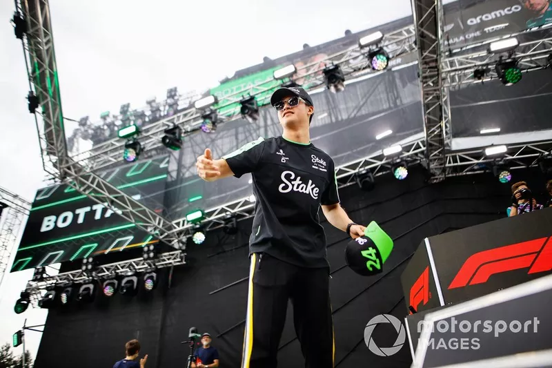 Zhou Guanyu, membre de l'équipe Stake F1 Kick Sauber, lance des casquettes aux fans depuis une scène.