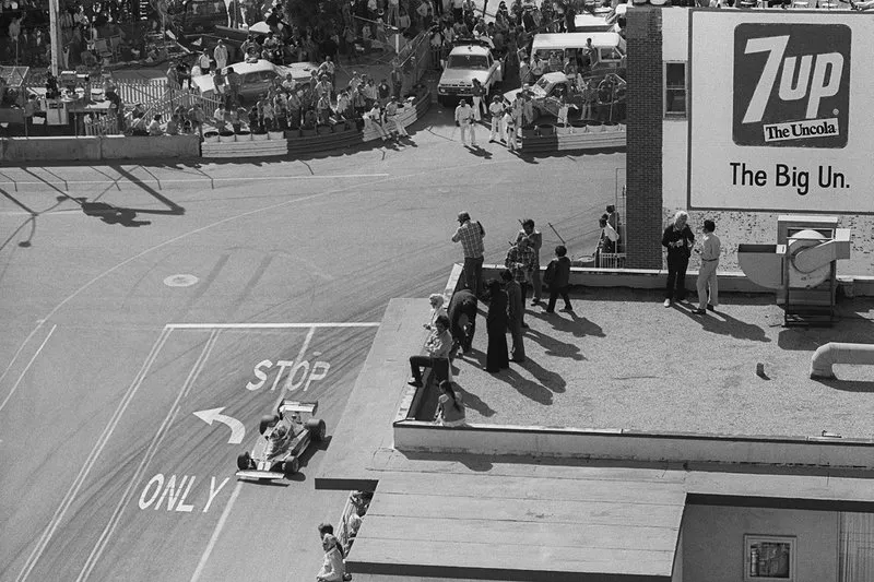 Niki Lauda, Ferrari 312T, is photographed by photographers perched on top of a building roof