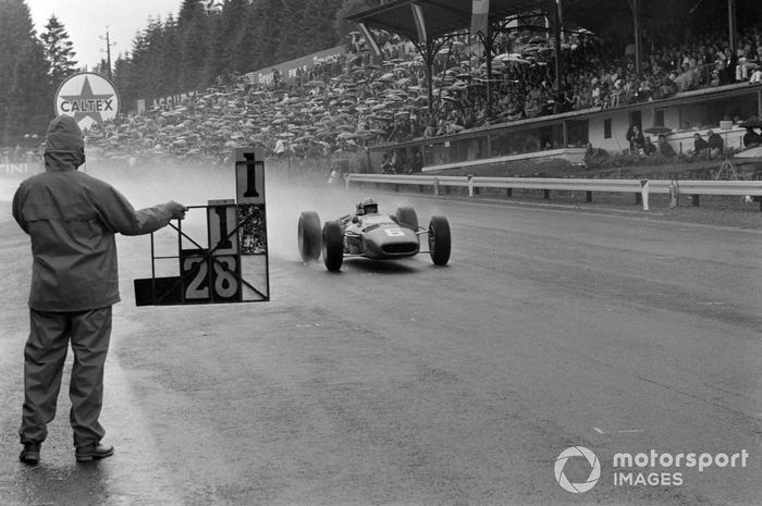 John Surtees, Ferrari 312, pasa por delante de una pizarra que le tiende un mecánico.