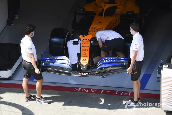 Les mécaniciens McLaren installent l'aileron avant sur la monoplace de Carlos Sainz Jr., McLaren MCL35 