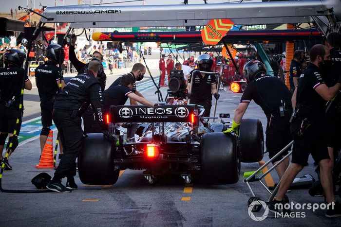 Los mecánicos llevan el coche de Lewis Hamilton, Mercedes W12, desde el pit lane