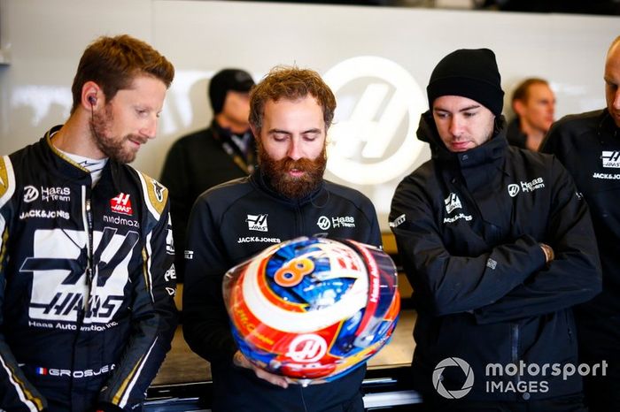 Romain Grosjean, Haas F1 Team, comenta el diseño de su casco con un compañero de equipo