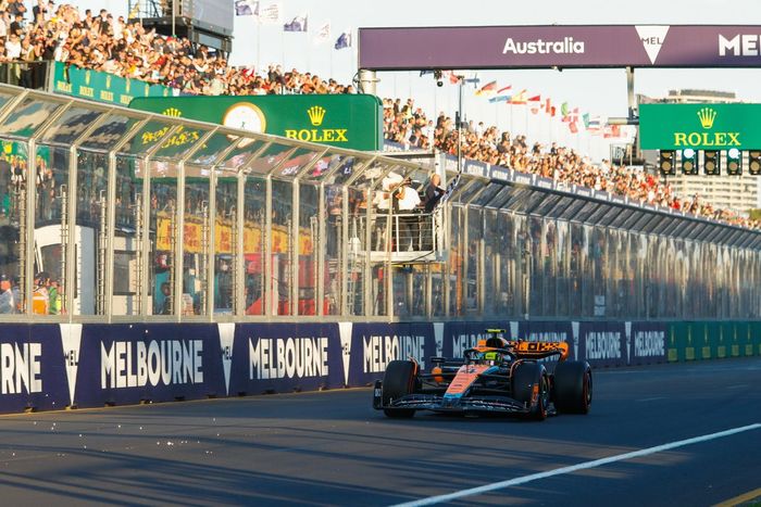 Lando Norris, McLaren MCL60, cruza la línea de meta mientras ondea la bandera a cuadros.