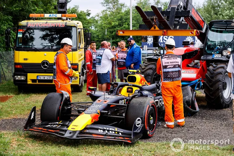 Les commissaires avec la voiture endommagée de Sergio Perez, Red Bull Racing RB20