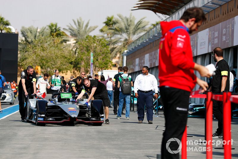 The Nissan team push a car in the pits
