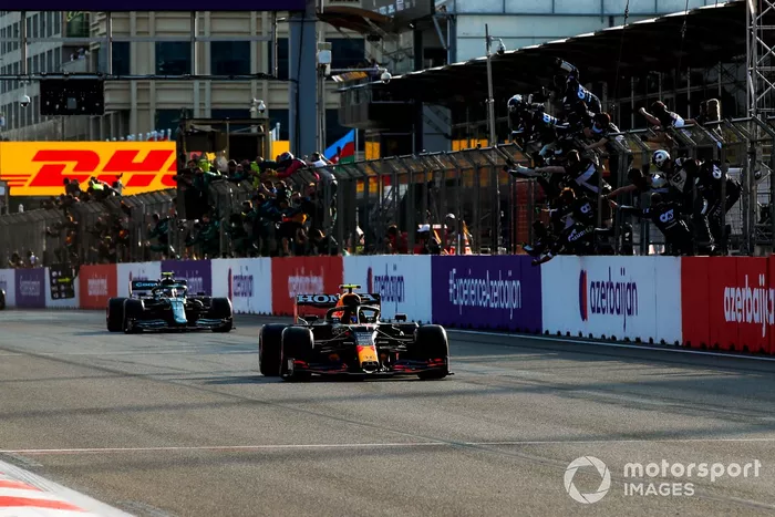 Sergio Pérez, Red Bull Racing RB16B, 1ª posición, toma la bandera a cuadros para alegría de su equipo en el muro de boxes
