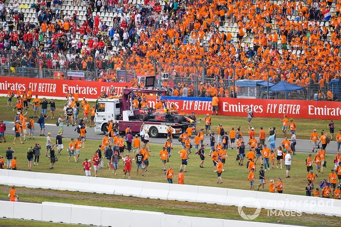 Los aficionados invaden el circuito después de la carrera mientras los oficiales retiran el coche de Pierre Gasly, Red Bull Racing RB15