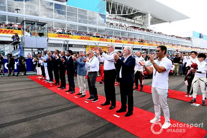 Los pilotos y los dignatarios se sitúan en la parrilla para escuchar el himno nacional antes de la salida