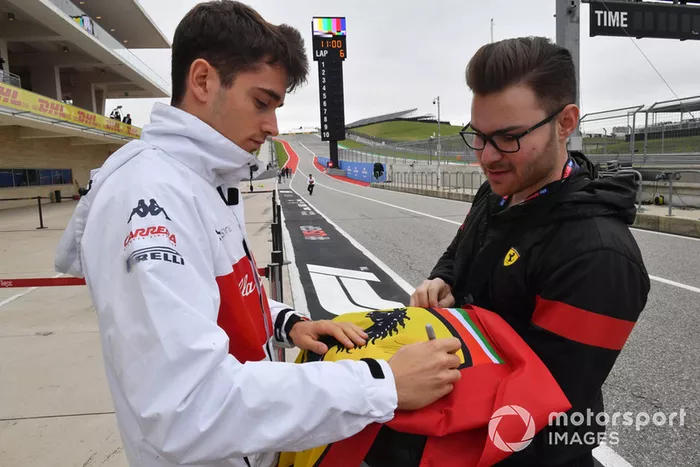 Charles Leclerc, Alfa Romeo Sauber F1 Team firma un autógrafo en una bandera de Ferrari