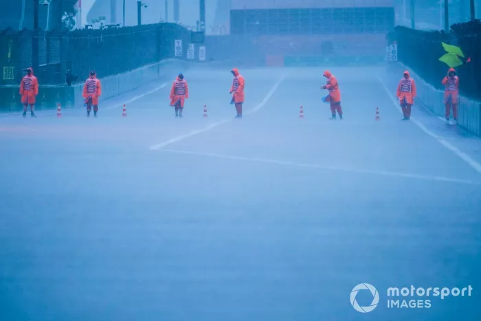Los comisarios colocan conos en la pista mientras cae la lluvia en Sochi
