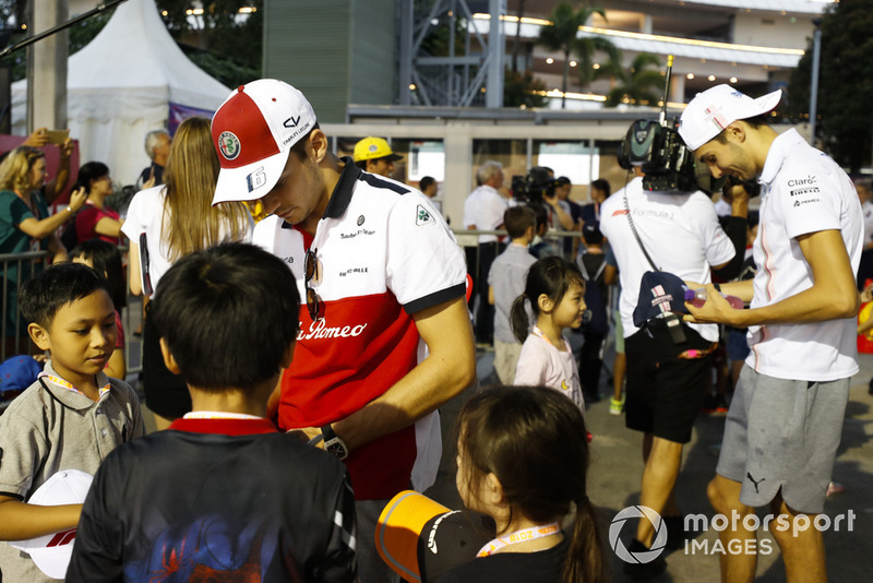 Charles Leclerc, Sauber, and Esteban Ocon, Racing Point Force India, sign autographs for grid kids