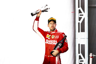 Sebastian Vettel, Ferrari, 2° classificato, lascia il podio con il suo trofeo e lo Champagne