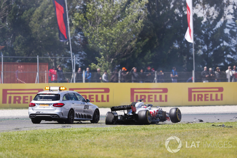 An official car stops next to the damaged Romain Grosjean Haas F1 Team VF-18