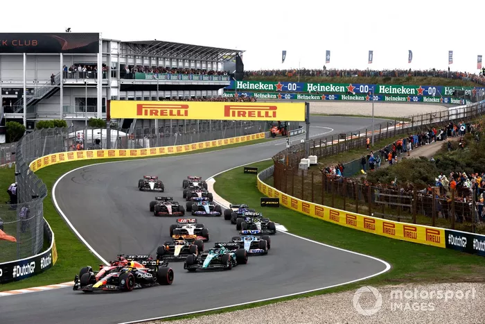 Sergio Pérez, Red Bull Racing RB19, lidera a Charles Leclerc, Ferrari SF-23, Lance Stroll, Aston Martin AMR23, Oscar Piastri, McLaren MCL60, y el resto del pelotón en la primera vuelta.
