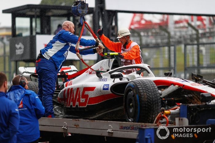 Mecánicos y comisarios descargan el coche dañado de Mick Schumacher, Haas VF-22, de una  plataforma después de la FP1