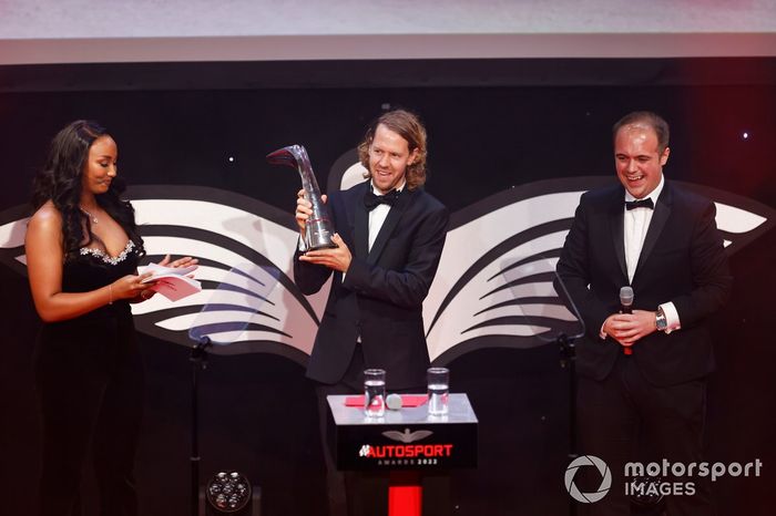 Sebastian Vettel sube al escenario para aceptar el premio a la trayectoria del periodista Luke Smith junto a la presentadora Naomi Schiff