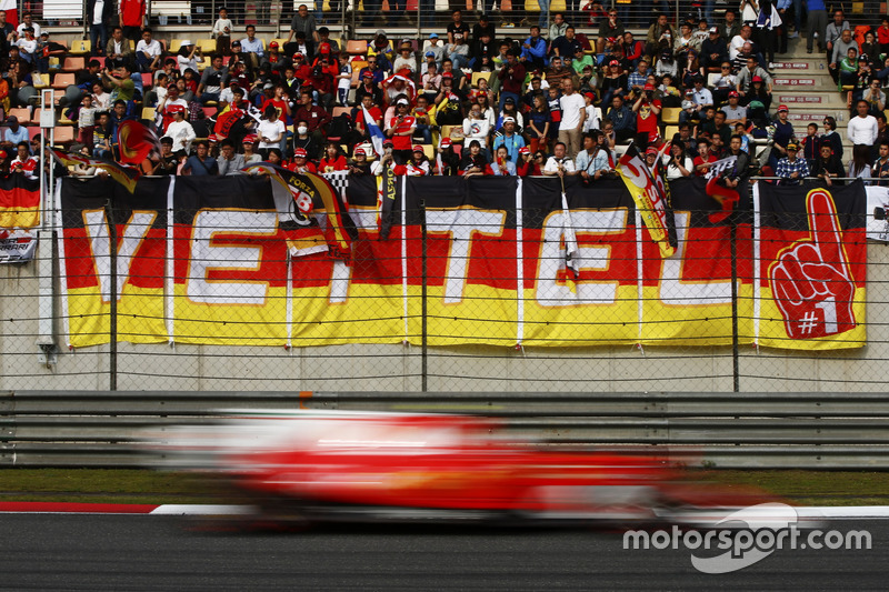 Une Ferrari passe devant une tribune avec de nombreux fans de Sebastian Vettel, Ferrari