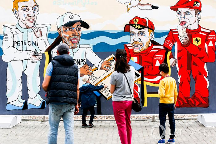Los fans miran obras de arte que representan a Valtteri Bottas, Mercedes AMG F1, Lewis Hamilton, Mercedes AMG F1, Sebastian Vettel, Ferrari y Kimi Raikkonen, Ferrari, jugando al backgammon