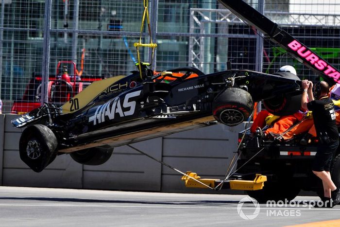 Oficiales retiran el coche dañado de Kevin Magnussen, Haas F1 Team VF-19, del circuito