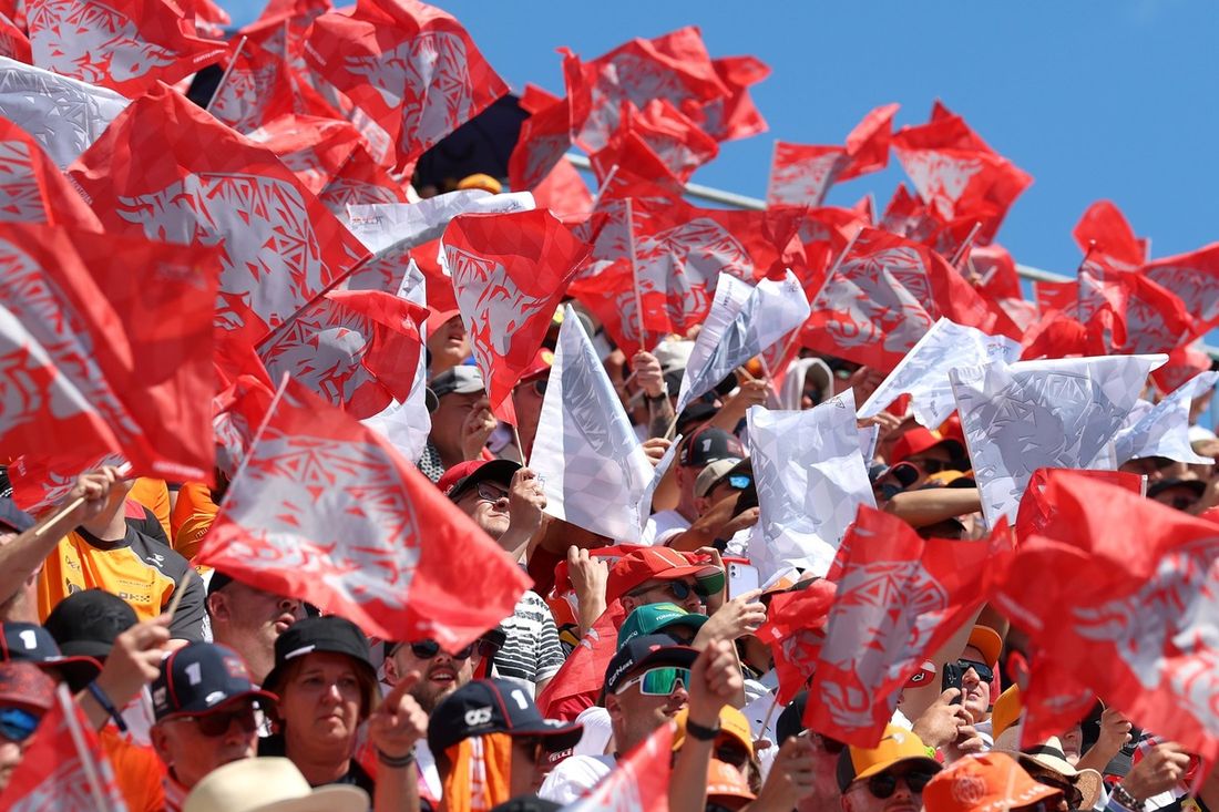 Fani machają biało-czerwonymi flagami na trybunach.