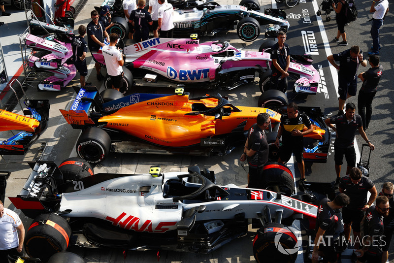 Cars of Kevin Magnussen, Lando Norris, Esteban Ocon, and Lewis Hamilton line up in the pit lane