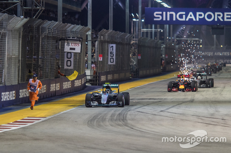Un oficial de pista corre por el circuito frente a Nico Rosberg
