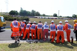 Oficiales de seguridad atienden al accidentado Sahara Force India de Sergio Pérez.