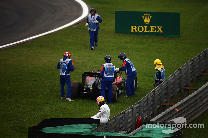 Fernando Alonso, McLaren observa como mariscales quitan su McLaren MP4-30 del circuito en la segunda