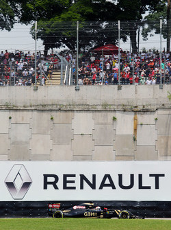 Romain Grosjean, Lotus F1 E23 passe devant un panneau publicitaire Renault