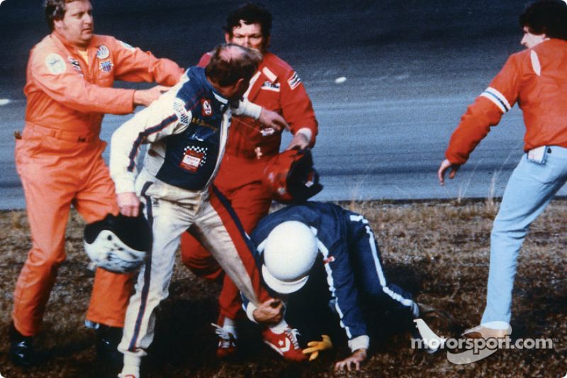 Cale Yarborough holds his helmet in his right hand while fighting off Bobby Allison with his left leg and Bobby's brother Donnie